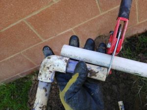 using the old PVC pipe as a guide to making cuts